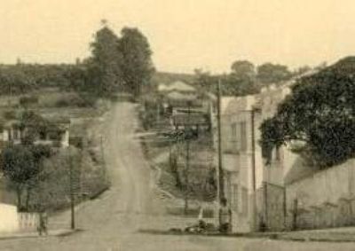 Foto antiga mostra a transi&ccedil;&atilde;o da antiga estrada cercada por eucaliptos para a atual Alameda Padre Magno, marcando o crescimento urbano do munic&iacute;pio.