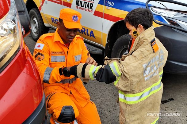Cabo Felipe termina de ajudar um menino a vestir a roupa de bombeiro. In&iacute;cio de um sonho?
