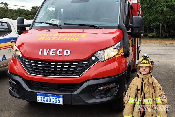 Crian&ccedil;a faz pose pra foto com roupa de bombeiro