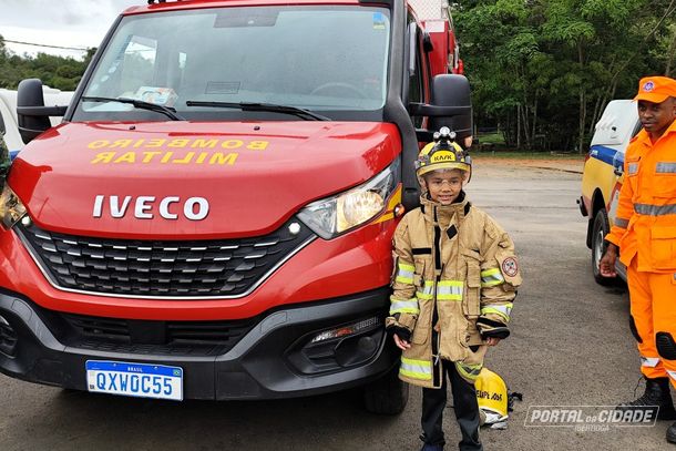 Menino ao lado da viatura dos bombeiros