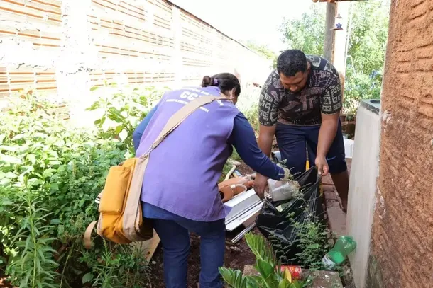 Agentes de endemias recolhem materiais em quintal tomado pelo mato (Foto: A. Frota)