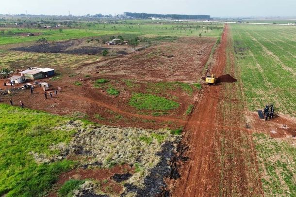 Vigiada por policiais militares (&agrave; direita), escavadeira abre valeta entre fazenda e &aacute;rea de ocupa&ccedil;&atilde;o (Foto: Leandro Holsbach)