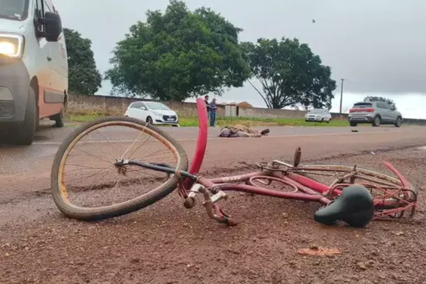 Bicicleta com roda retorcida e o corpo do ciclista no meio da pista; ao fundo o carro que o atropelou (Foto: Leandro Holsbach)