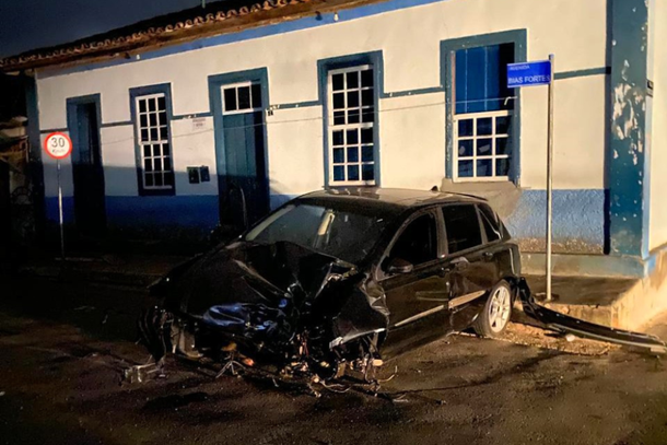 Carro destru&iacute;do em frente a casar&atilde;o no centro. Do lado esquerdo, &eacute; poss&iacute;vel ver a placa com o limite de velocidade de 30 km/h