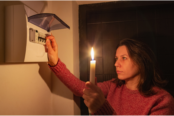 Mulher com vela verifica circuito de luz